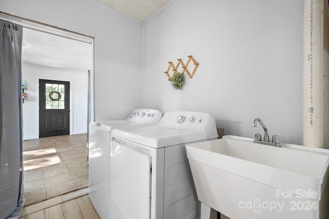 laundry room with sink, independent washer and dryer, and light wood-type flooring