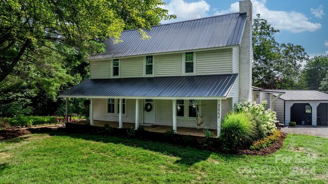 view of front of house featuring a garage, covered porch, an outdoor structure, and a front lawn