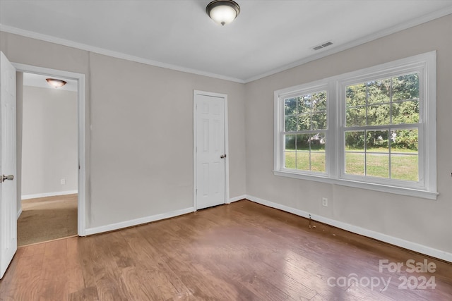 empty room featuring crown molding and wood-type flooring