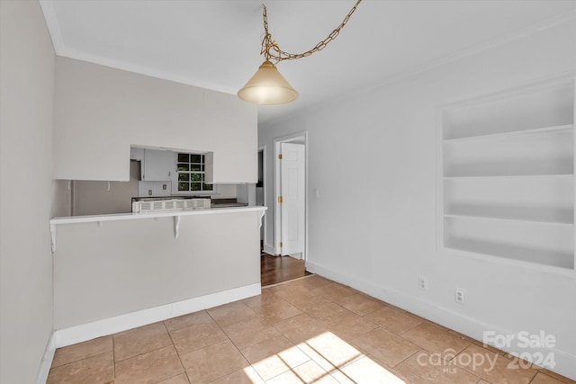 kitchen featuring light tile patterned flooring, built in shelves, a kitchen bar, kitchen peninsula, and pendant lighting