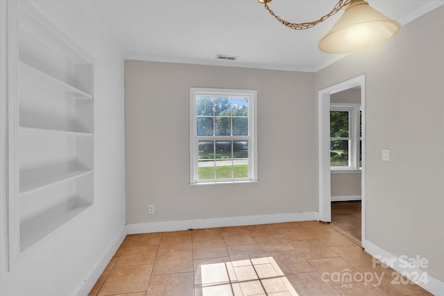 spare room featuring ornamental molding, light tile patterned floors, and built in shelves