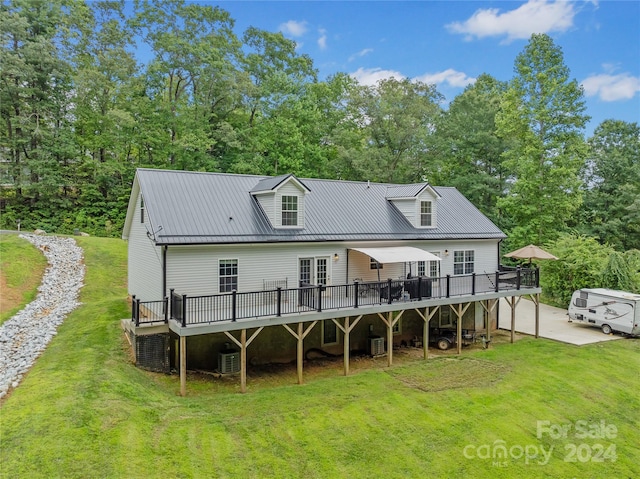 back of house featuring a yard, a wooden deck, a garage, and central AC