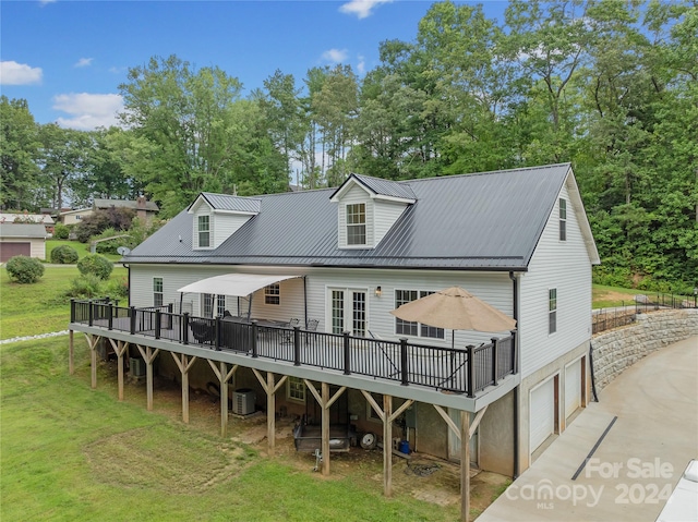 rear view of property featuring a lawn, a wooden deck, central AC unit, a garage, and french doors