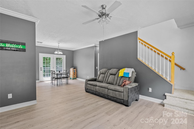 living room with ceiling fan with notable chandelier, ornamental molding, french doors, and light hardwood / wood-style floors