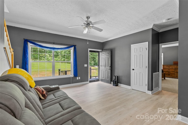 living room featuring ornamental molding, ceiling fan, light hardwood / wood-style floors, and a textured ceiling