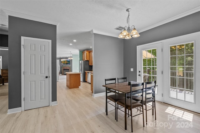 dining room featuring light hardwood / wood-style floors, crown molding, a chandelier, and a textured ceiling