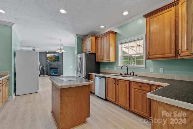 kitchen with crown molding, ceiling fan with notable chandelier, stainless steel appliances, light hardwood / wood-style floors, and sink