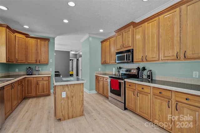 kitchen featuring light wood-type flooring, a textured ceiling, a kitchen island, stainless steel appliances, and ornamental molding