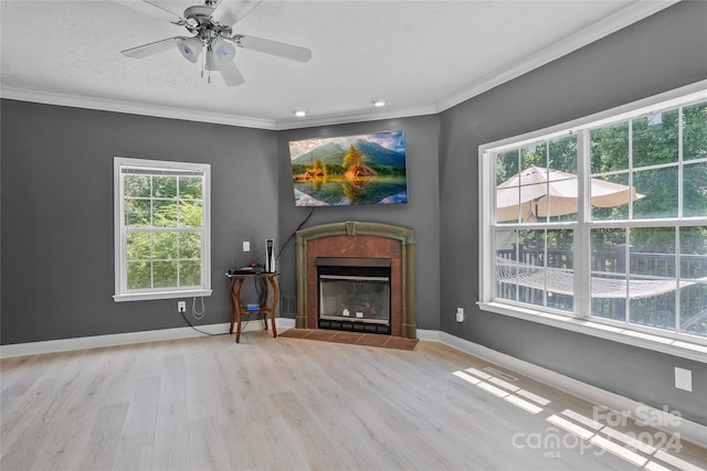 unfurnished living room with light hardwood / wood-style floors, ornamental molding, a fireplace, and ceiling fan