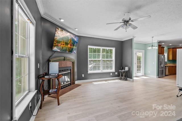 living room with light hardwood / wood-style floors, ornamental molding, a fireplace, and ceiling fan