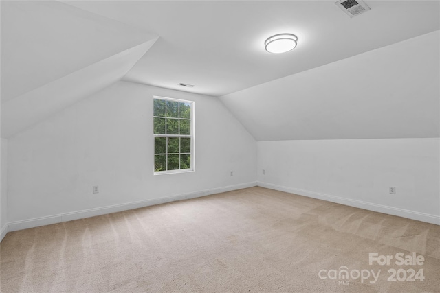 bonus room featuring vaulted ceiling and light colored carpet