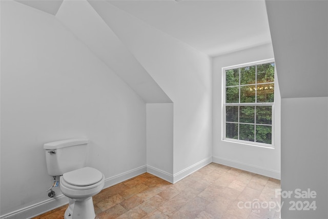 bathroom featuring tile patterned floors, lofted ceiling, and toilet