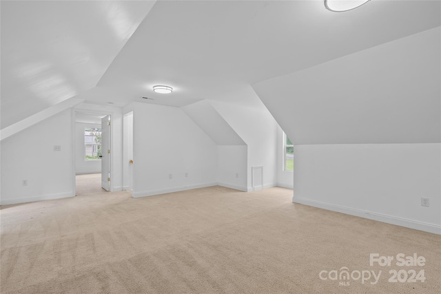 bonus room with vaulted ceiling, light colored carpet, and plenty of natural light