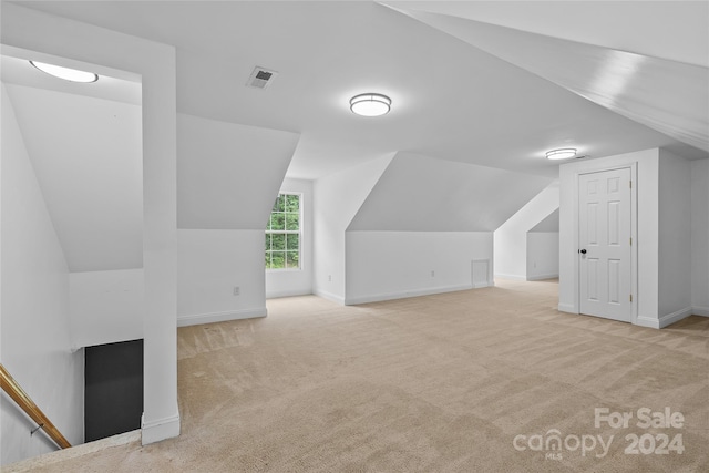 bonus room with lofted ceiling and light colored carpet