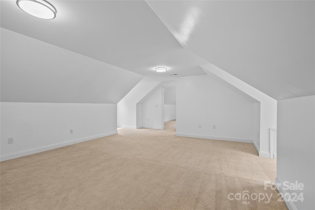 additional living space featuring lofted ceiling and light colored carpet