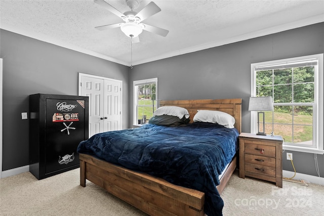 carpeted bedroom featuring multiple windows, a textured ceiling, and ceiling fan