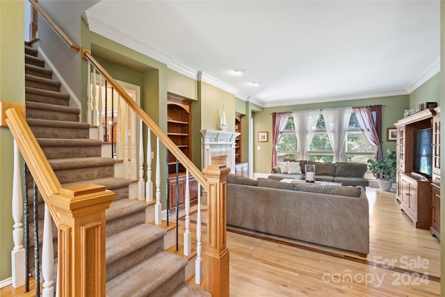 living area with baseboards, a fireplace, wood finished floors, ornamental molding, and stairway