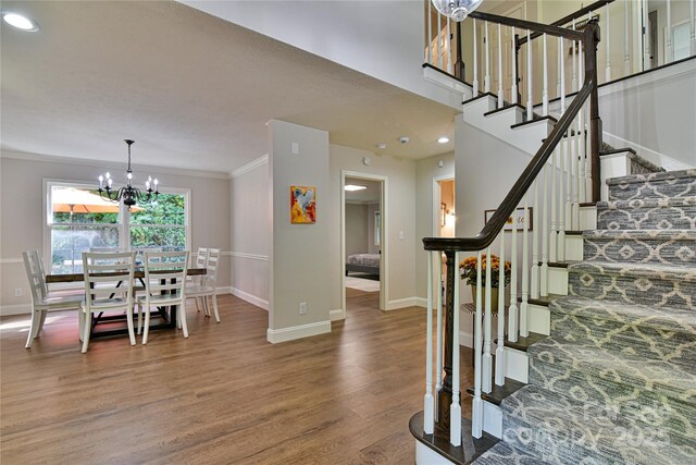 foyer entrance with ornamental molding, wood-type flooring, and a notable chandelier