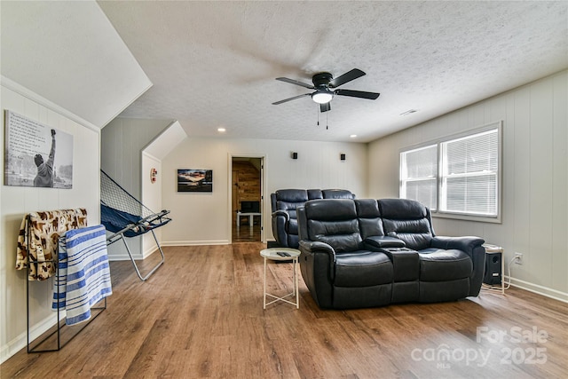 home theater room featuring hardwood / wood-style flooring, ceiling fan, and a textured ceiling