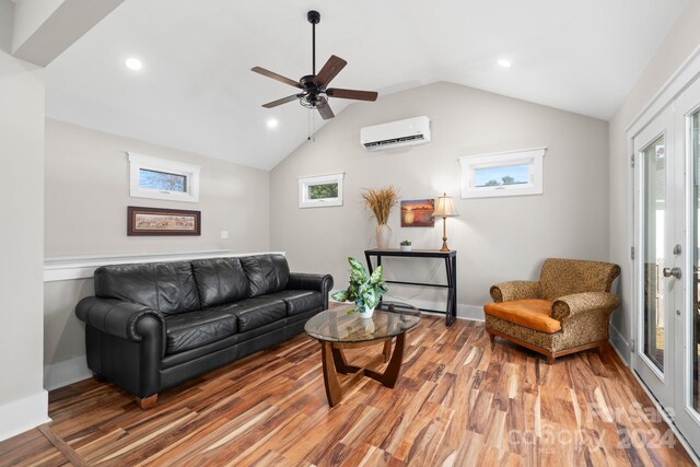 living room with plenty of natural light, a wall mounted air conditioner, hardwood / wood-style floors, and vaulted ceiling