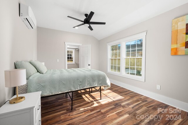 bedroom with a wall unit AC, ceiling fan, dark hardwood / wood-style flooring, and vaulted ceiling