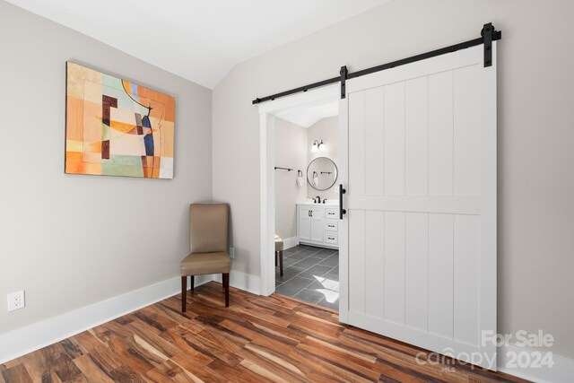 living area featuring a barn door, dark hardwood / wood-style flooring, and lofted ceiling