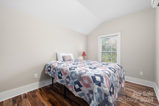 bedroom with vaulted ceiling, a wall unit AC, and dark hardwood / wood-style floors