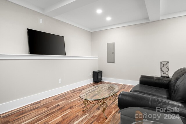 living room featuring electric panel, beamed ceiling, and hardwood / wood-style flooring