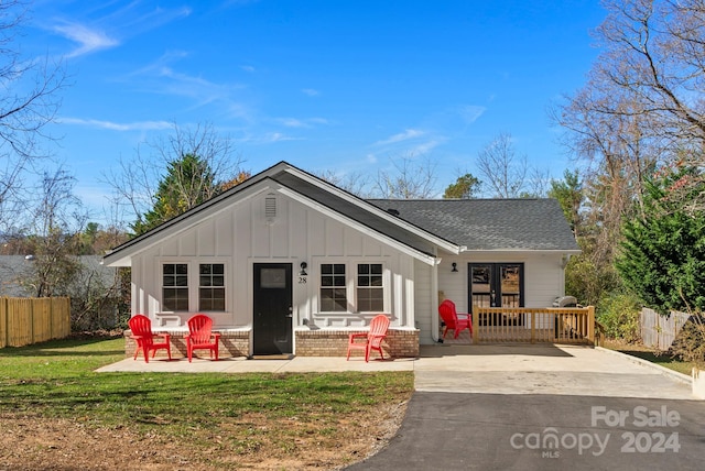 rear view of house featuring a lawn and a porch