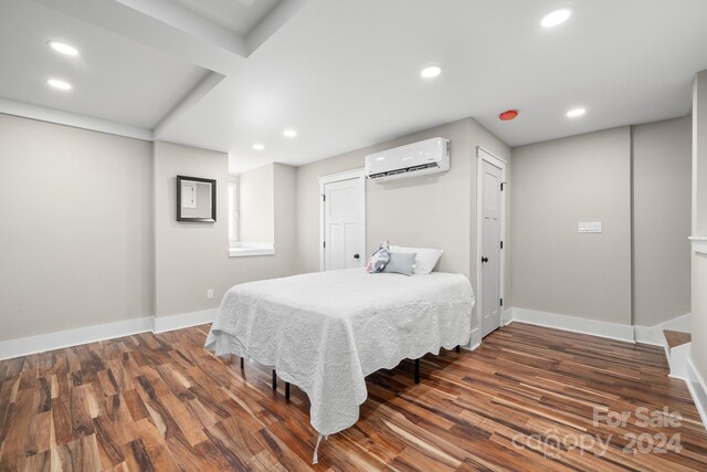 bedroom featuring a wall mounted AC and dark hardwood / wood-style flooring