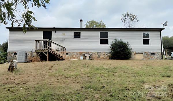 rear view of property featuring cooling unit and a yard