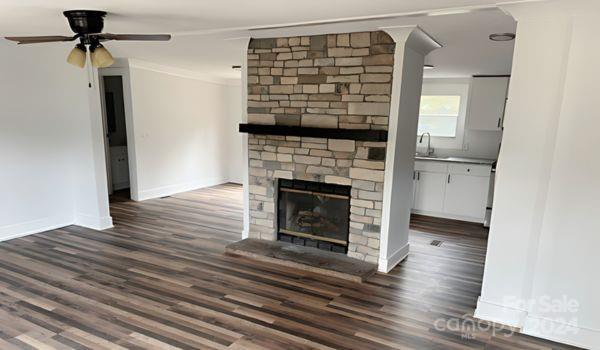 unfurnished living room featuring ornamental molding, dark hardwood / wood-style flooring, sink, a brick fireplace, and ceiling fan