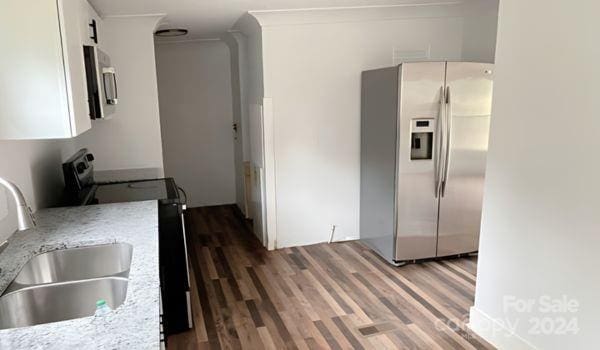 kitchen featuring dark wood-type flooring, sink, ornamental molding, light stone countertops, and appliances with stainless steel finishes