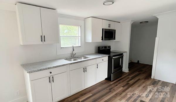 kitchen with appliances with stainless steel finishes, sink, dark hardwood / wood-style floors, and white cabinets