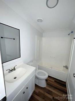 full bathroom with shower / washtub combination, vanity, hardwood / wood-style flooring, and toilet