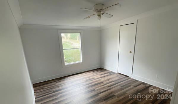 empty room with ceiling fan, dark hardwood / wood-style floors, and crown molding