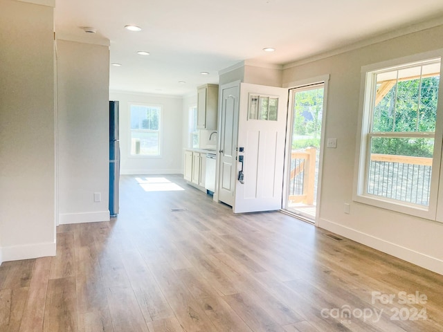 entrance foyer with light wood-type flooring, crown molding, and a wealth of natural light