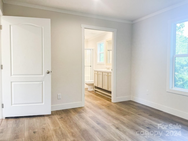 unfurnished bedroom featuring light wood-type flooring, ensuite bath, ornamental molding, and sink