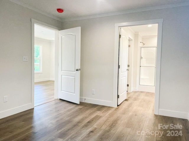 empty room with light hardwood / wood-style floors and ornamental molding