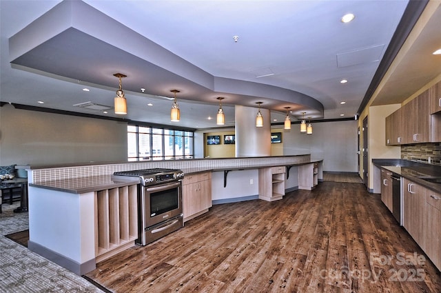 kitchen with open floor plan, stainless steel appliances, dark countertops, and pendant lighting