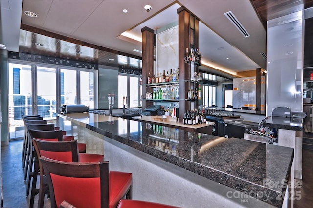 bar with a raised ceiling, visible vents, a sink, and a dry bar