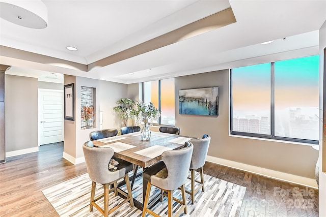 dining room featuring recessed lighting, a raised ceiling, baseboards, and wood finished floors