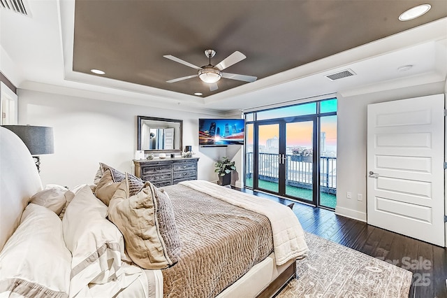 bedroom with dark wood-style floors, access to outside, a raised ceiling, and visible vents