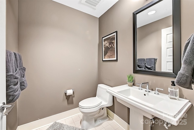 half bath featuring tile patterned flooring, toilet, a sink, visible vents, and baseboards