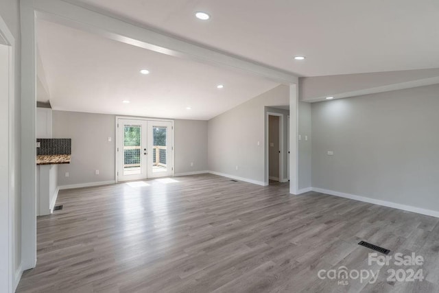 unfurnished living room featuring lofted ceiling with beams, light hardwood / wood-style flooring, and french doors