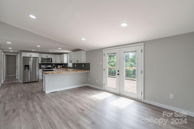 kitchen featuring french doors, tasteful backsplash, kitchen peninsula, stainless steel appliances, and white cabinets