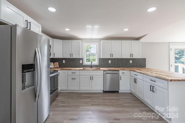 kitchen with white cabinetry, butcher block counters, and appliances with stainless steel finishes