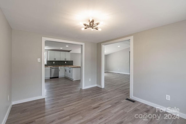 unfurnished living room featuring a notable chandelier and hardwood / wood-style flooring