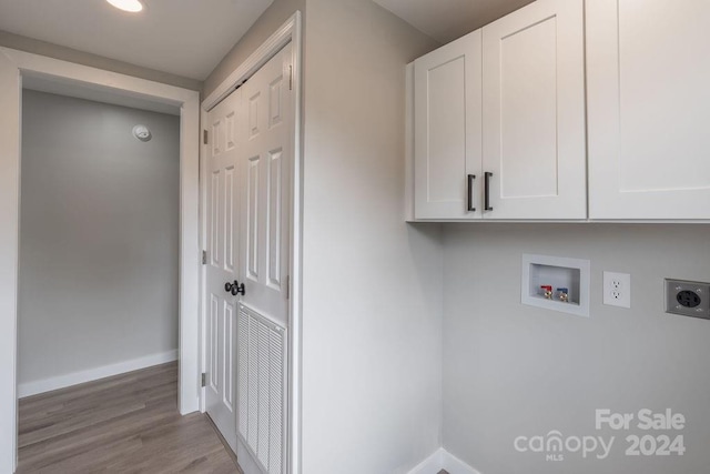 laundry area with cabinets, hookup for an electric dryer, light hardwood / wood-style floors, and hookup for a washing machine