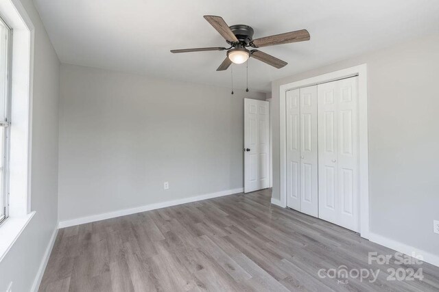 unfurnished bedroom with ceiling fan, a closet, and light wood-type flooring